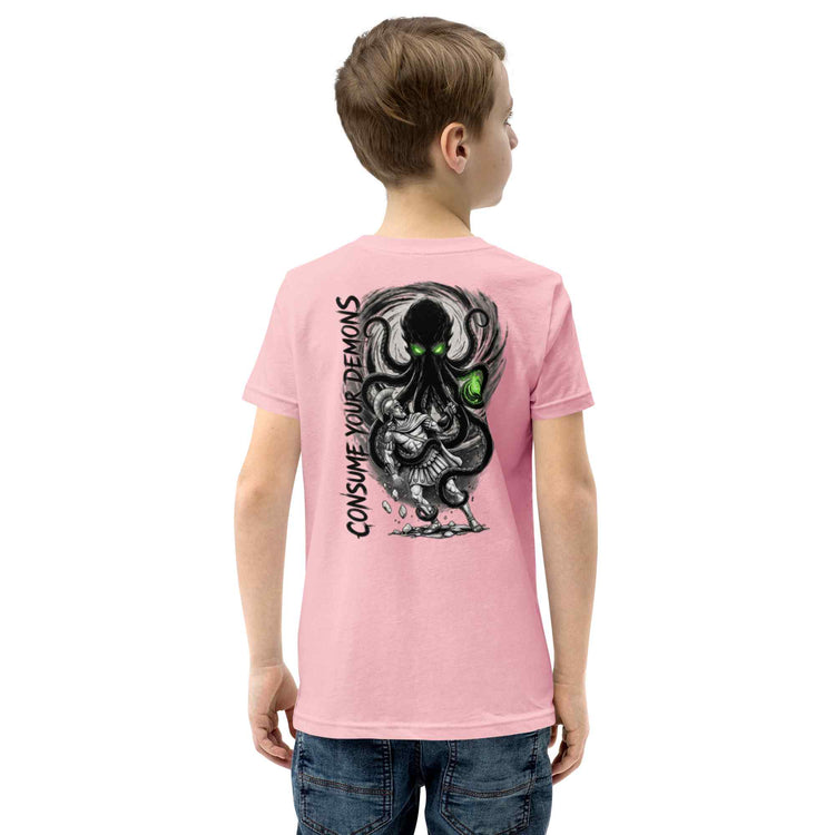 A child model from the back wearing a light pink t-shirt with a large black and gray octopus graphic and the text 'CONSUME YOUR DEMONS' printed on the back, paired with blue jeans against a plain white background.