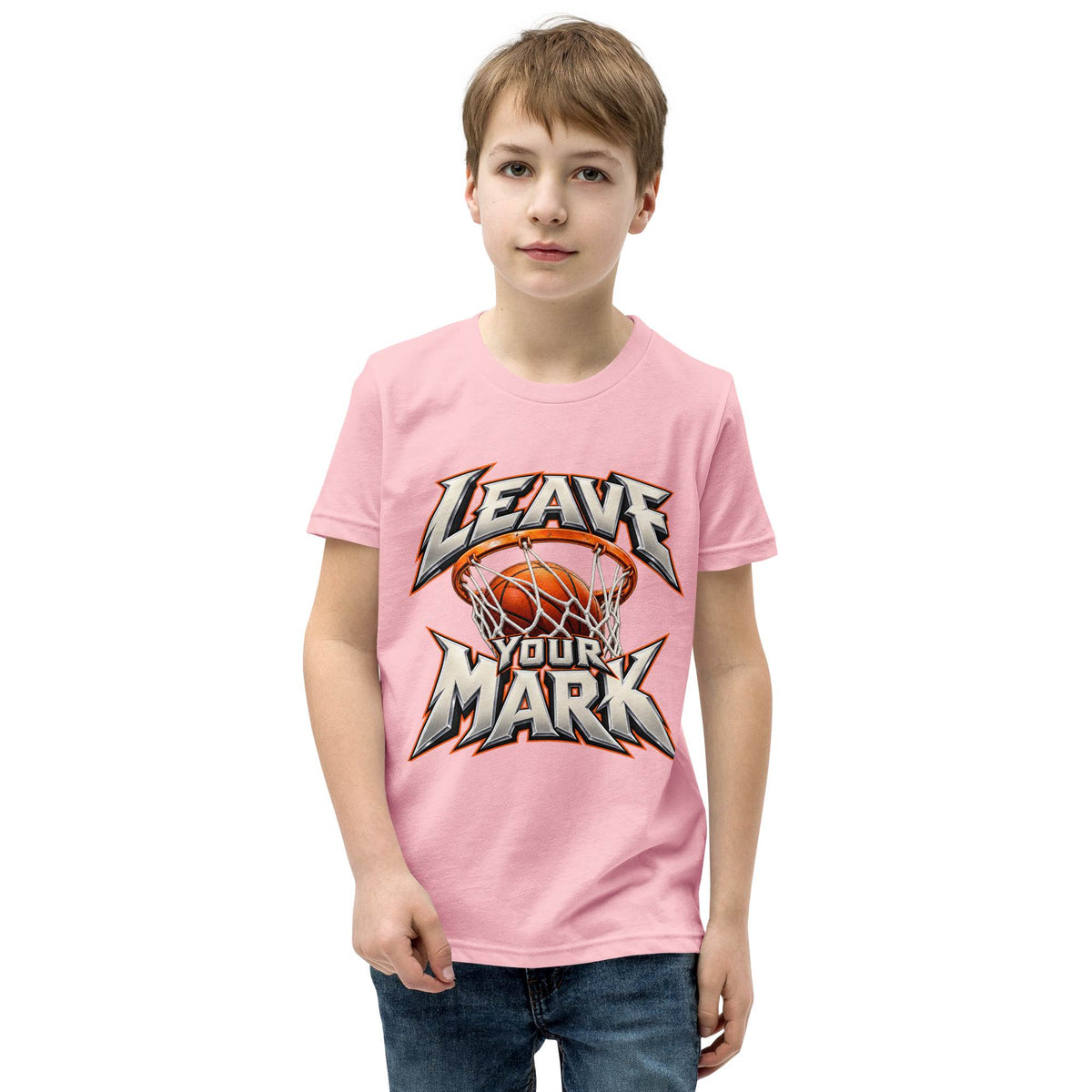 A young boy wearing a light pink t-shirt with a 'LEAVE YOUR MARK' basketball graphic, paired with blue jeans, set against a plain white background.