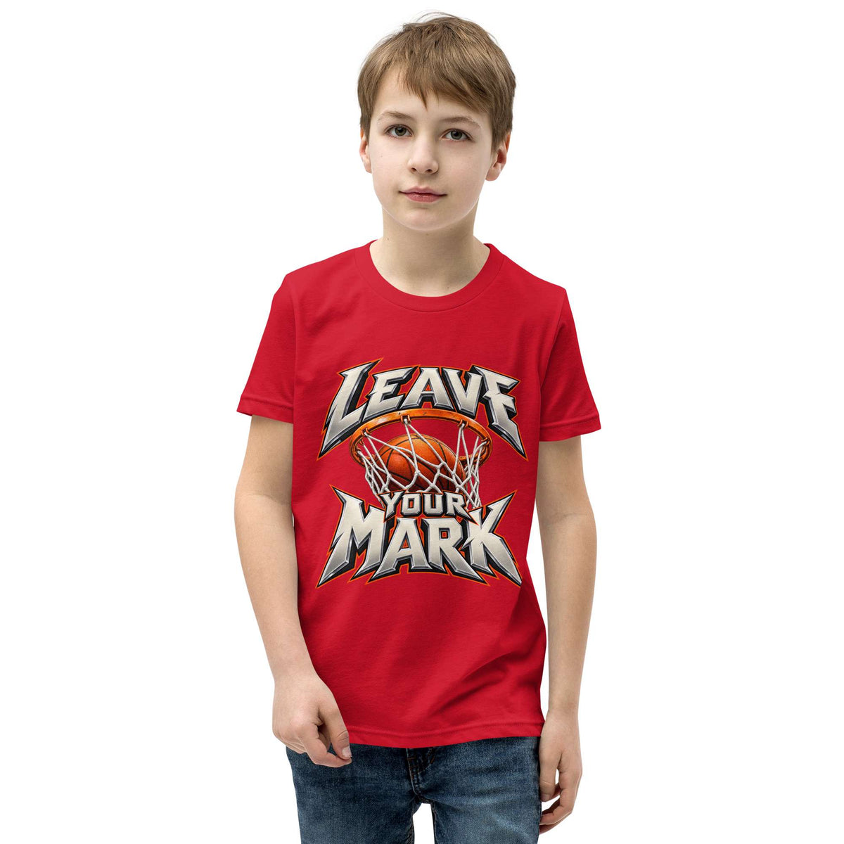 A young boy wearing a red short-sleeve t-shirt with a 'LEAVE YOUR MARK' basketball graphic on the front, paired with blue jeans, set against a plain white background.