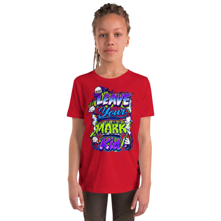 A young girl with braided hair wearing a bright red short-sleeve t-shirt with a colorful graphic that reads 'LEAVE YOUR MARK Kid' in stylized lettering, set against a plain white background.