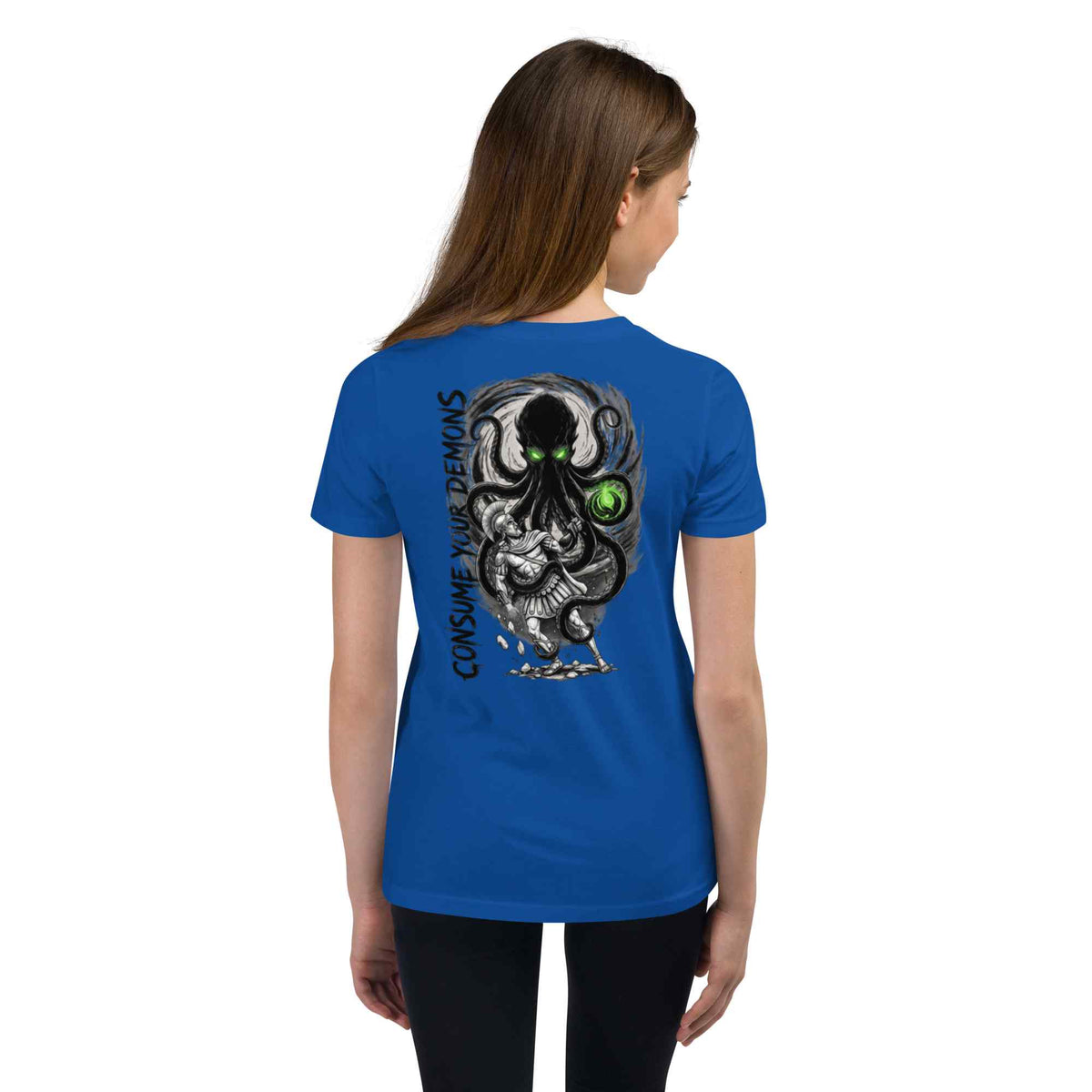 A woman viewed from the back wearing a royal blue short-sleeve t-shirt with a large graphic print on the back. The graphic features a black and gray octopus-like creature with a glowing green eye, kraken and vertical text reading 'CONSUME YOUR DEMONS'.