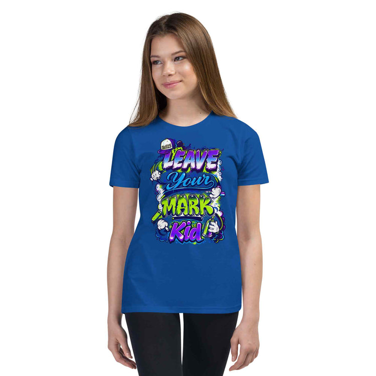 A young woman modeling a royal blue t-shirt with a colorful graphic that reads 'LEAVE YOUR MARK Kid' surrounded by cartoon characters, set against a plain white background.