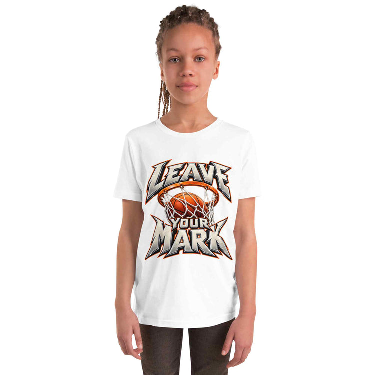 A young girl with braided hair wearing a white short-sleeve t-shirt with a basketball-themed graphic that reads 'LEAVE YOUR MARK'. The graphic features a basketball in a hoop with a metallic silver, orange, and black design.