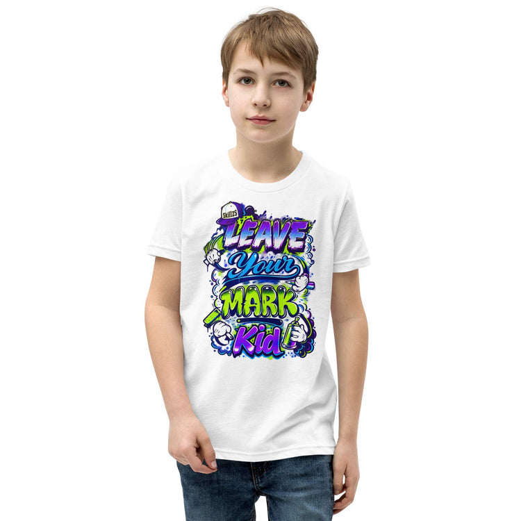 A young boy wearing a white crewneck t-shirt with a colorful graphic that reads 'LEAVE YOUR MARK KID' in purple, green, and blue stylized lettering, paired with blue jeans, set against a plain white background.