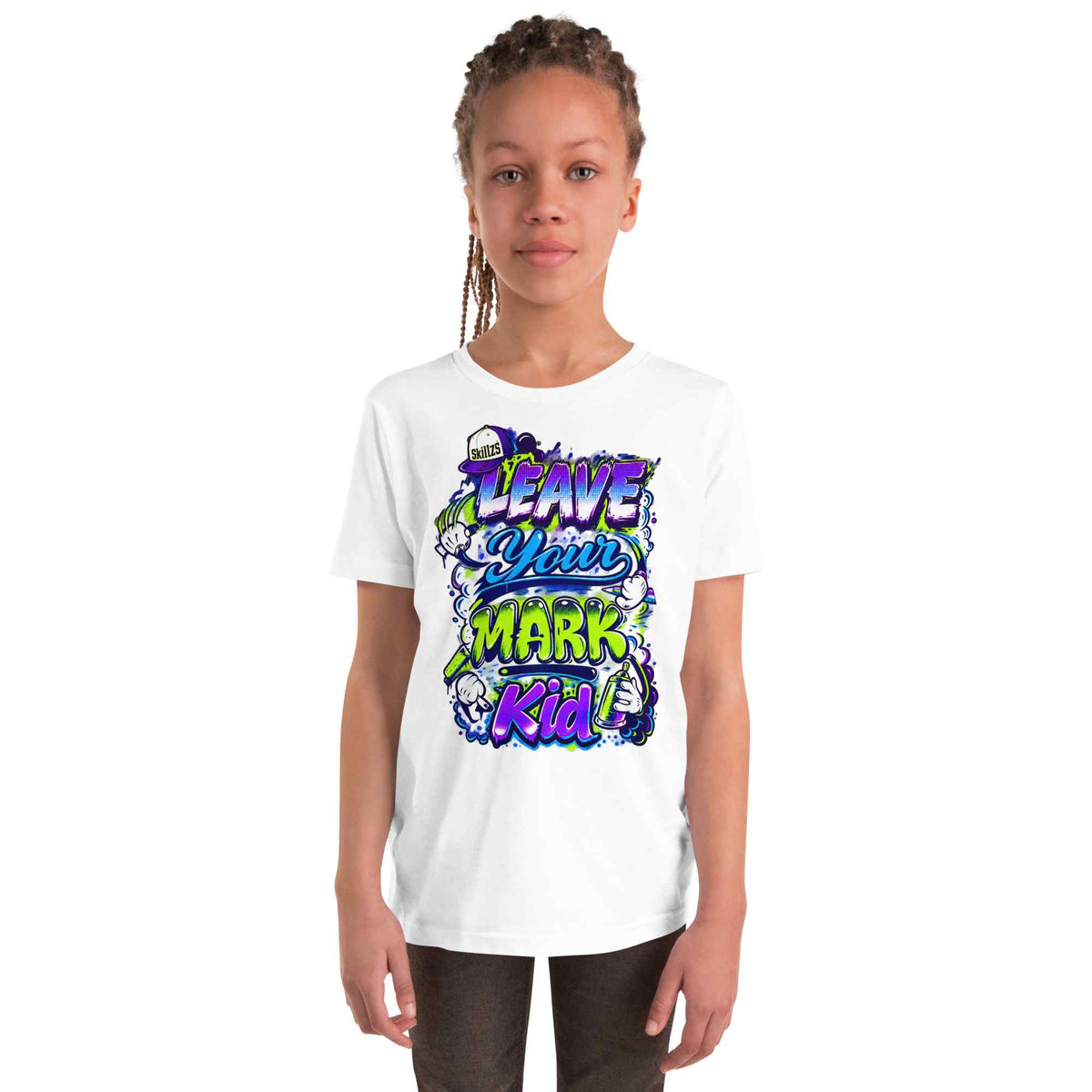 A young girl with braided hair stands against a plain white background wearing a white short-sleeve t-shirt with a colorful graphic print that reads 'LEAVE YOUR MARK Kid'.